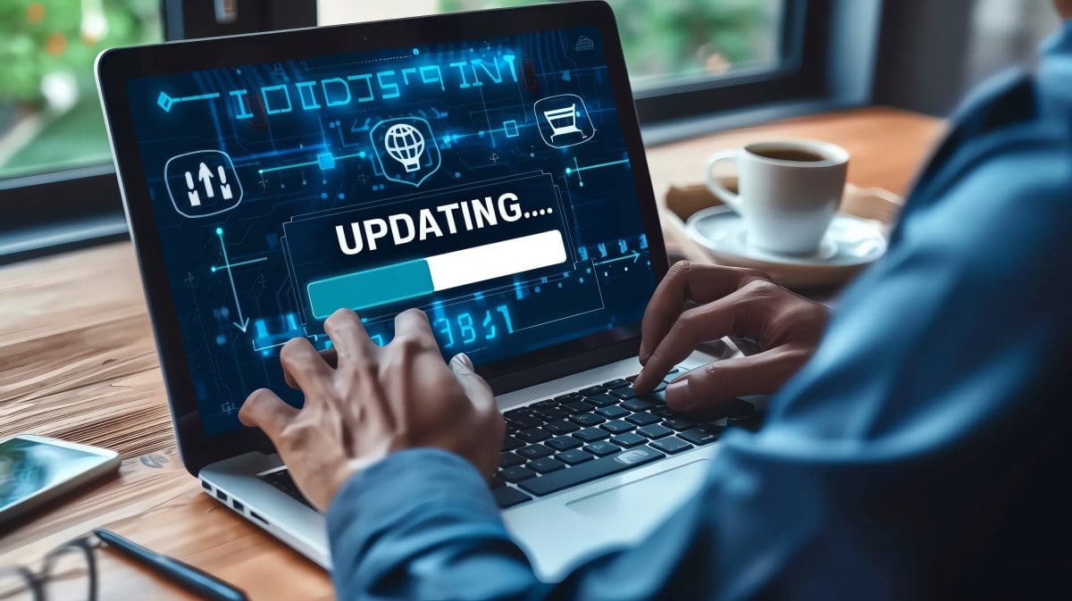 Person operating laptop with updating system progress on screen, technology and software development concept.